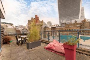 London City 1 Bed with Roof Terrace في لندن: فناء على طاولة وكراسي على شرفة