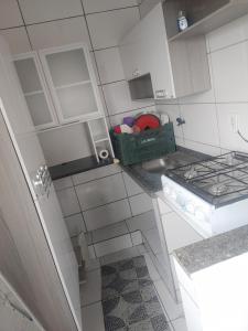 a small white kitchen with a basket on the counter at Quitinete in Rio de Janeiro
