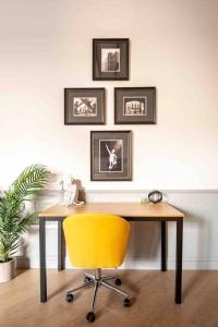 un bureau avec une chaise jaune et des photos sur le mur dans l'établissement Lovely Condo in Downtown Birmingham, à Birmingham