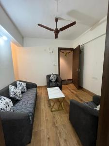 uma sala de estar com 2 sofás e uma ventoinha de tecto em Royal Palm's Private 1 BHK Garden Apartment em Pune