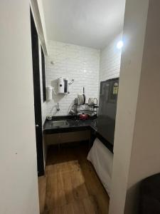 uma pequena cozinha com um balcão preto e um lavatório em Royal Palm's Private 1 BHK Garden Apartment em Pune