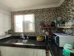 a kitchen with a sink and a microwave at Tchê Hostel in Porto Seguro