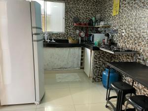 La cuisine est équipée d'un réfrigérateur et d'un évier. dans l'établissement Tchê Hostel, à Porto Seguro