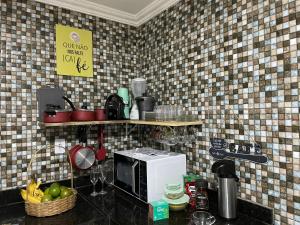 a kitchen with a counter top with a microwave at Tchê Hostel in Porto Seguro