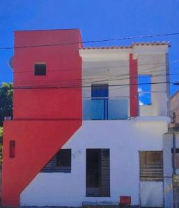 um edifício branco e vermelho com uma diagonal vermelha em Tchê Hostel em Porto Seguro