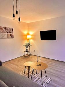 a living room with two tables and a flat screen tv at PrimeBnb Bad Salzungen in Bad Salzungen