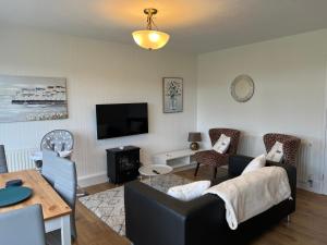 ein Wohnzimmer mit Sofa und Tisch in der Unterkunft CHINE COTTAGE self-catering coastal bungalow in rural West Wight in Freshwater