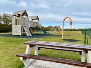 ein Park mit einer Holzbank und einem Spielplatz in der Unterkunft CHINE COTTAGE self-catering coastal bungalow in rural West Wight in Freshwater