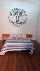 a bedroom with a bed with a tree on the wall at Posada the secret in Colonia del Sacramento