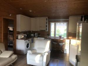 uma cozinha com uma cadeira branca e um fogão forno superior em Modern cottage by the private lake em Lappeenranta