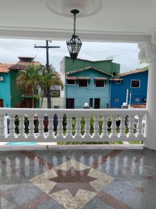 un balcón con barandilla blanca y un edificio azul en Na Casa da Santa Hostel & Bistrô - Tudo a pé - 100 mt da Passarela do Álcool, en Porto Seguro