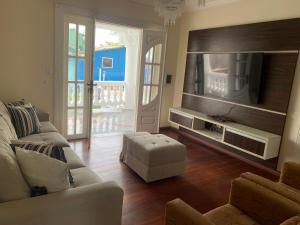 a living room with a couch and a tv at Na Casa da Santa Hostel & Bistrô - Tudo a pé - 100 mt da Passarela do Álcool in Porto Seguro