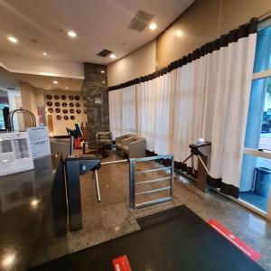 a waiting room with a table and chairs and a window at Suíte ampla no melhor da Barra da Tijuca in Rio de Janeiro