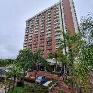 a large pink building with palm trees in front of it at Suíte ampla no melhor da Barra da Tijuca in Rio de Janeiro