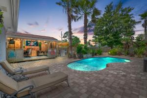 Una piscina en un patio con sillas y una casa. en Shipwrecked - Private Pool Home, Game Room, 5 Min to Beach, Pets OK, & More!, en Panama City Beach