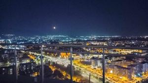 - une vue sur la ville la nuit avec des lumières dans l'établissement Sunrise Sky Lux Apartment, 33rd floor, Pool and Fitness Included, à Skopje