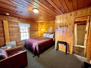 ein Schlafzimmer mit einem Bett in einer Holzhütte in der Unterkunft Yellowstone Cabins and RV in West Yellowstone