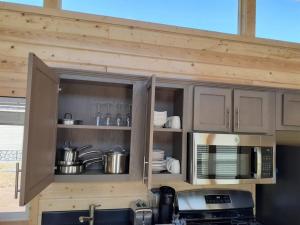 a kitchen with wooden cabinets with pots and pans at 091 Star Gazing Tiny Home near Grand Canyon South Rim Sleeps 8 in Valle