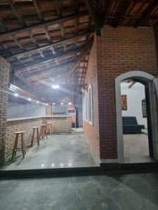 an empty room with tables and a brick wall at Casa Relaxemar in Caraguatatuba