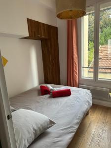 um quarto com 2 camas com almofadas vermelhas e uma janela em Cosy 2 pièces Parc Georges Brassens em Paris