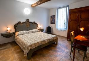 Schlafzimmer mit einem Bett, einem Tisch und einem Schreibtisch in der Unterkunft Fermo della Guazzona in Busseto