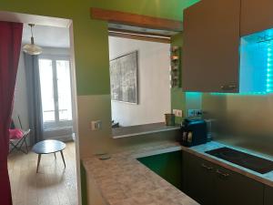 uma cozinha com paredes verdes, um lavatório e uma mesa em Cosy 2 pièces Parc Georges Brassens em Paris