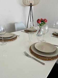 a white table with plates and wine glasses and flowers at Schöne zentrale Wohnung Nähe HB in Germersheim