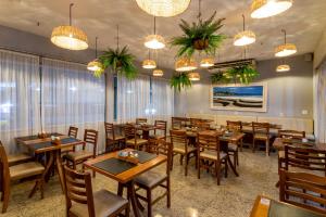 uma sala de jantar com mesas, cadeiras e lustres em Fluminense Hotel no Rio de Janeiro