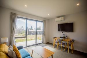 a living room with a couch and a table and a large window at Skyblue Tekapo in Lake Tekapo