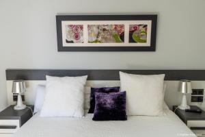 1 dormitorio con cama blanca y almohadas moradas en Apartamento - Riba De Sella, en Ribadesella