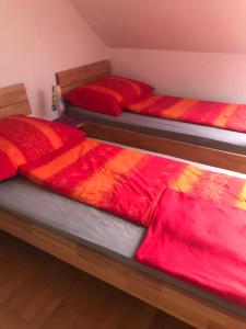 2 Betten in einem Zimmer mit roten und orangefarbenen Decken in der Unterkunft Vermieterei in Oberwölbling