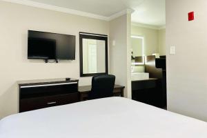 Dormitorio con cama, escritorio y TV en Rodeway Inn Lemon Grove San Diego East, en Lemon Grove