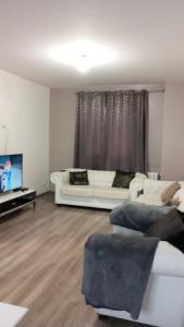 a living room with two white couches and a flat screen tv at Maison au calme in Livry-Gargan