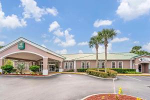 a hotel with a parking lot and palm trees at Quality Inn Conference Center at Citrus Hills in Hernando