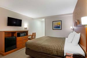 a hotel room with a bed and a flat screen tv at Rodeway Inn Terre Haute in Terre Haute
