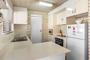 een witte keuken met een wastafel en een koelkast bij Kenway Lodge in Ballina