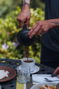 een persoon die koffie in een kopje giet op een tafel bij Cedrela Eco-Lodge & Restaurante in El Copey