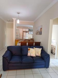 a blue couch in a living room with a kitchen at Apartamento da Martha in Ubatuba