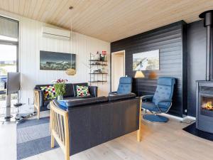 8 person holiday home in L gstrup في Løgstrup: غرفة معيشة بها موقد وكراسي زرقاء