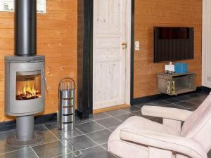 a fireplace in a living room with two chairs and a television at 8 person holiday home in Vinderup in Vinderup