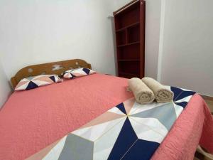 een slaapkamer met een bed met een rode deken en kussens bij D’Clau City Appartment in Iquitos