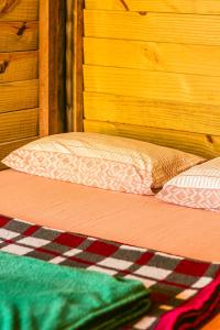a bed with a wooden headboard and a pillow on it at Camping Atobá Praia do Sono in Paraty