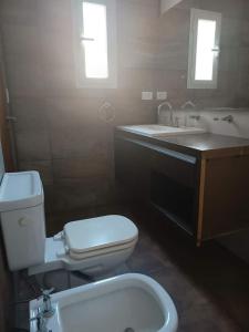 La salle de bains est pourvue de toilettes blanches et d'un lavabo. dans l'établissement Casa de 2 plantas con parque y quincho, à Mar del Plata