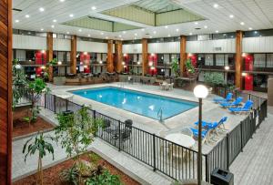 una piscina cubierta en un gran edificio con sillas y mesas en Ramada by Wyndham Gulfport I-10 Diamondhead en Diamondhead
