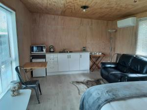 ein Wohnzimmer mit einem Sofa und einer Küche in der Unterkunft Brighton Beach in Dunedin