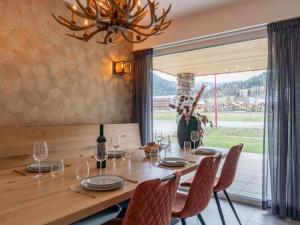 une salle à manger avec une table en bois, des chaises et un lustre dans l'établissement Bergzicht 2A, à Sankt Lorenzen ob Murau