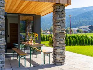 a patio with a table and chairs and a stone wall at Bergzicht in Sankt Lorenzen ob Murau