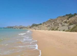 a sandy beach with the ocean and mountains in the background at La Foggia seaside paradise in Siculiana