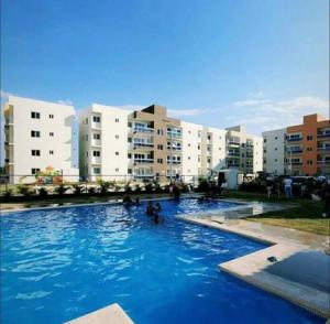 a swimming pool with blue water in front of buildings at Primer Nivel. Apto de 2 Habitaciones La Vega in Concepción de La Vega