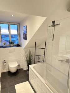 uma casa de banho branca com uma banheira e um WC em Oasis Appart - Wohnen am Elbtal - Balkon - Netflix - Tiefgarage em Dresden